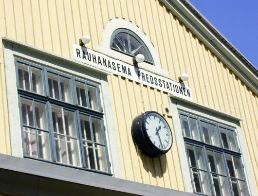Yksityiskohta Rauhanaseman julkisivusta: Kellotaulu ja kyltti, jossa lukee Rauhanasema Fredsstationen